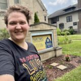 Kori, in a black shirt, standing in front of a sign that says Fair Oaks Presbyterian Church on it.